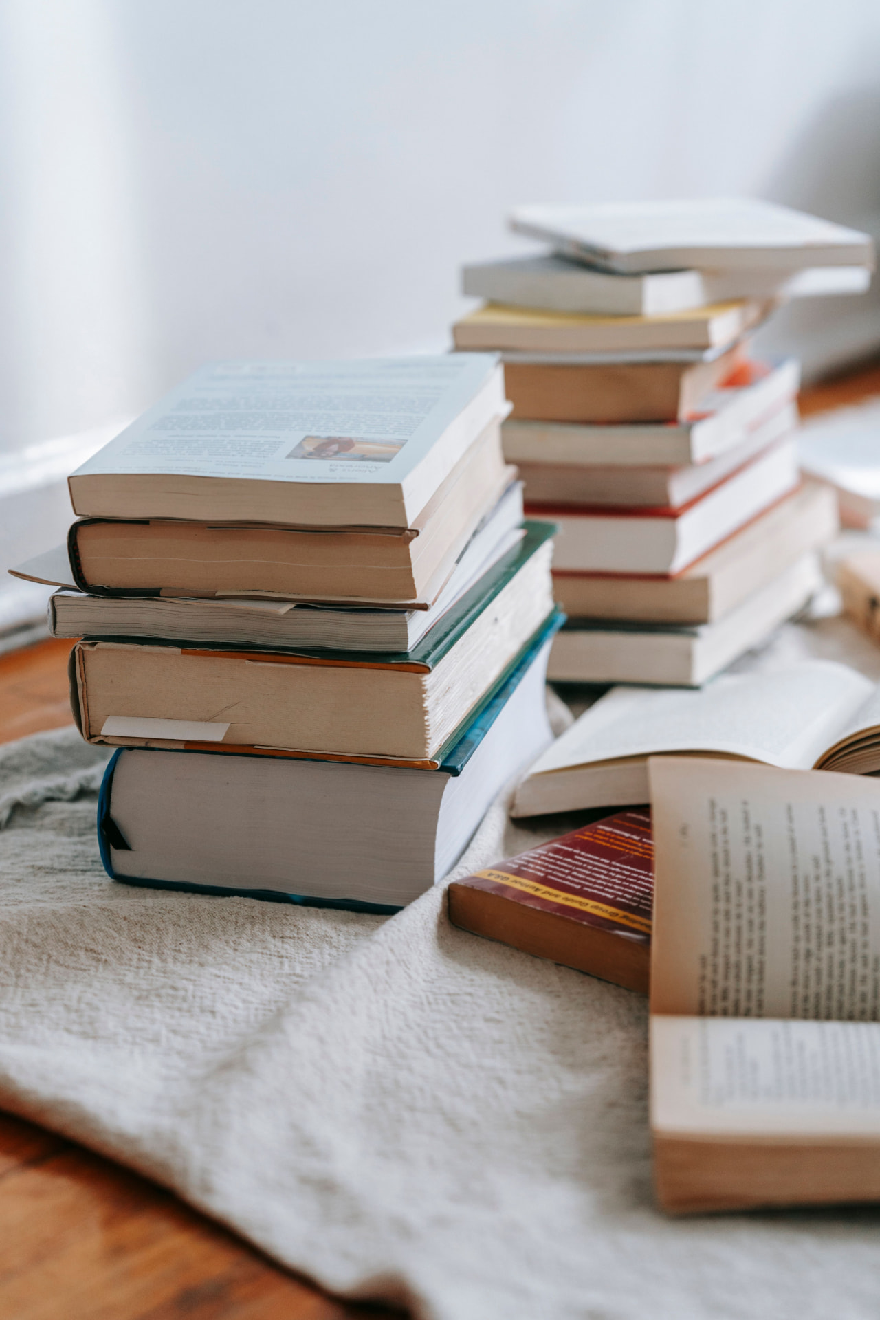 Stacks of open books resting on a soft linen throw